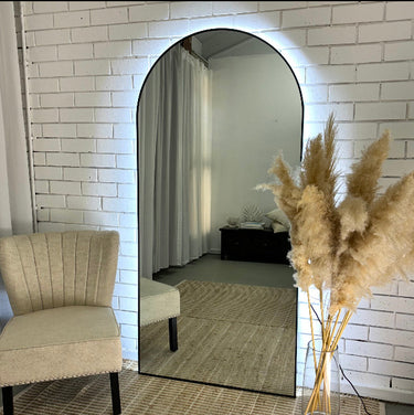 Luna backlit LED arch mirror in gold glowing on a wall