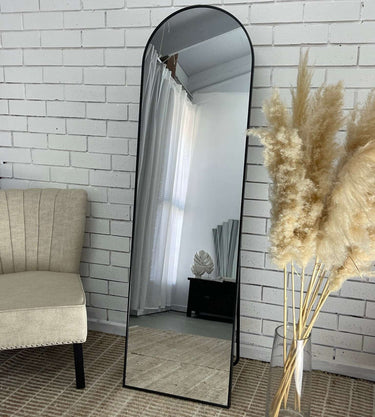 Black standing arch mirror in a dressing area