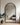 An enormous black arc mirror leaning against the wall in the living room.
