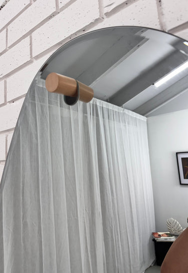 Asymmetrical organic mirror mounted on a brick wall