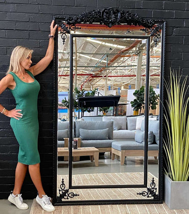 Extra large ornate panelled mirror leaning against a wall