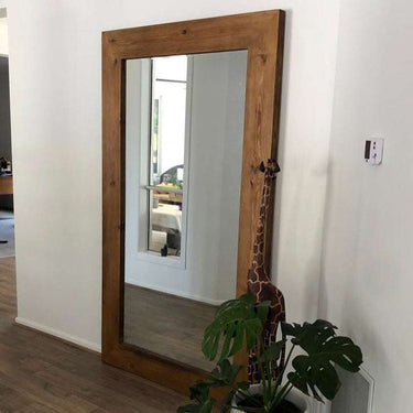 Extra large wooden mirror leaning against a wall