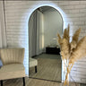Luna backlit LED arch mirror in gold glowing on a wall
