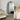 Minimalist white arch mirror leaning against a wall