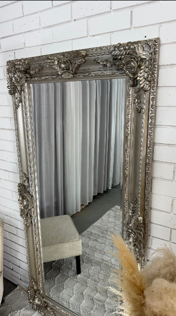 Ornate full length mirror with a carved wooden frame