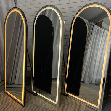 Arched LED mirror lit up in a bathroom
