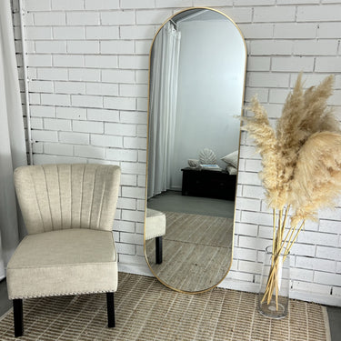 Pill oval full length mirror leaning against a wall