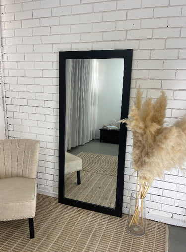 Black real wood mirror leaning against a wall