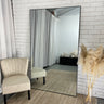 Slim black frame full length mirror leaning in a hallway