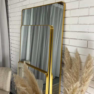 Gold curved-corner mirror leaning against a wall
