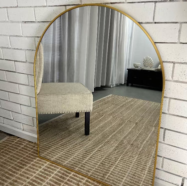 Small gold arch mirror above a bathroom vanity